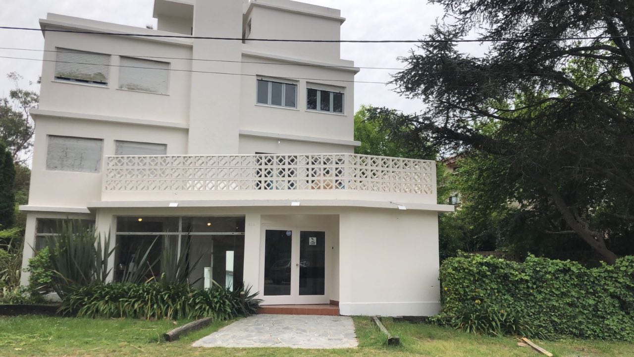 Fachada de Black Suites Pinamar - Edificio blanco con balcón y jardín